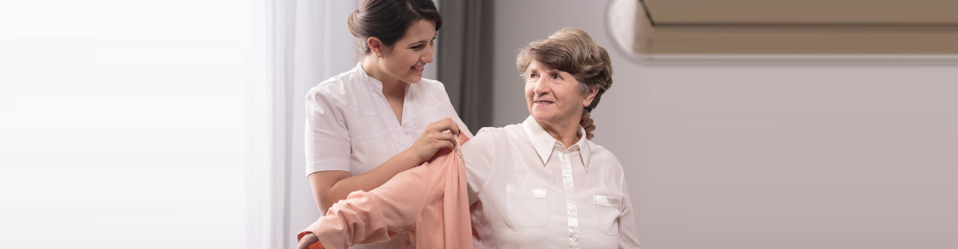 lady caregiver dressing the old woman